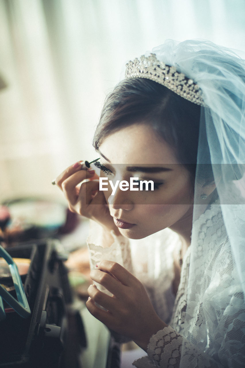 Bride applying make-up while sitting at home