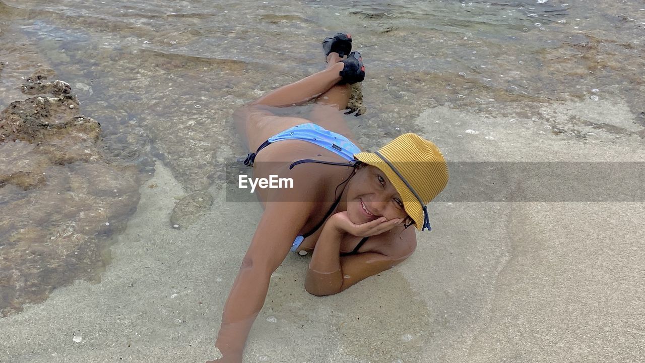 HIGH ANGLE VIEW OF CHILD LYING ON BEACH