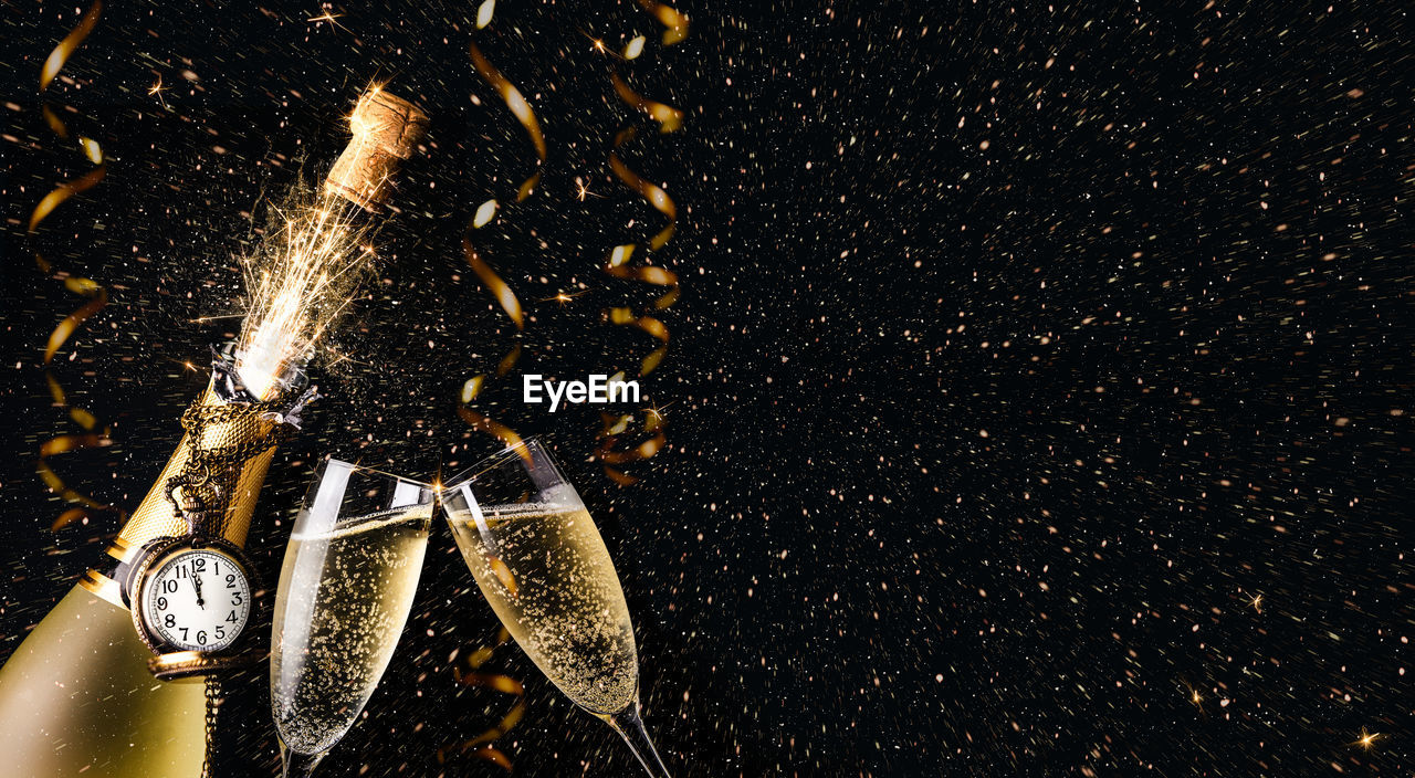 Digital composite image of champagne bottle exploding against black background