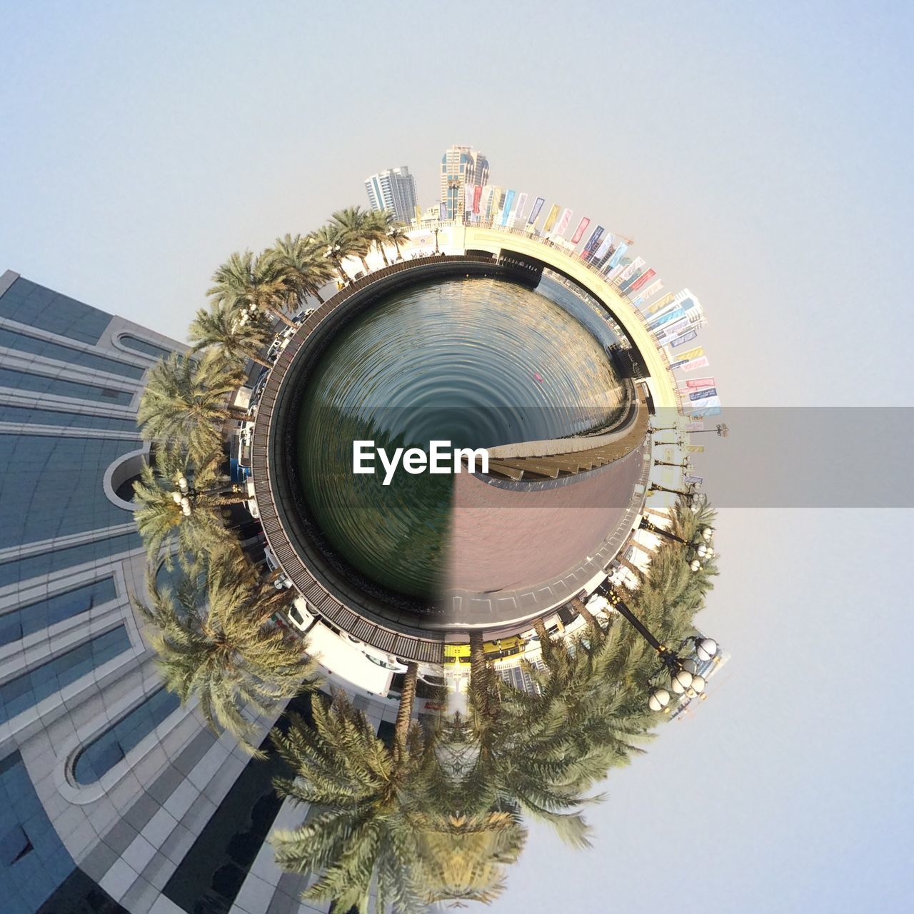 Fish-eye lens of cityscape and palm trees with water against sky