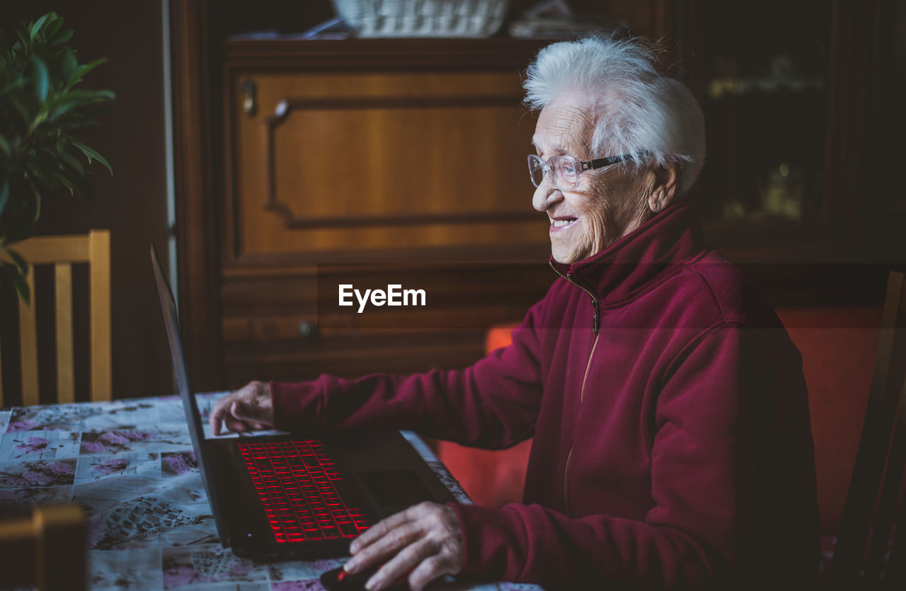 Smiling senior woman using laptop while sitting at home