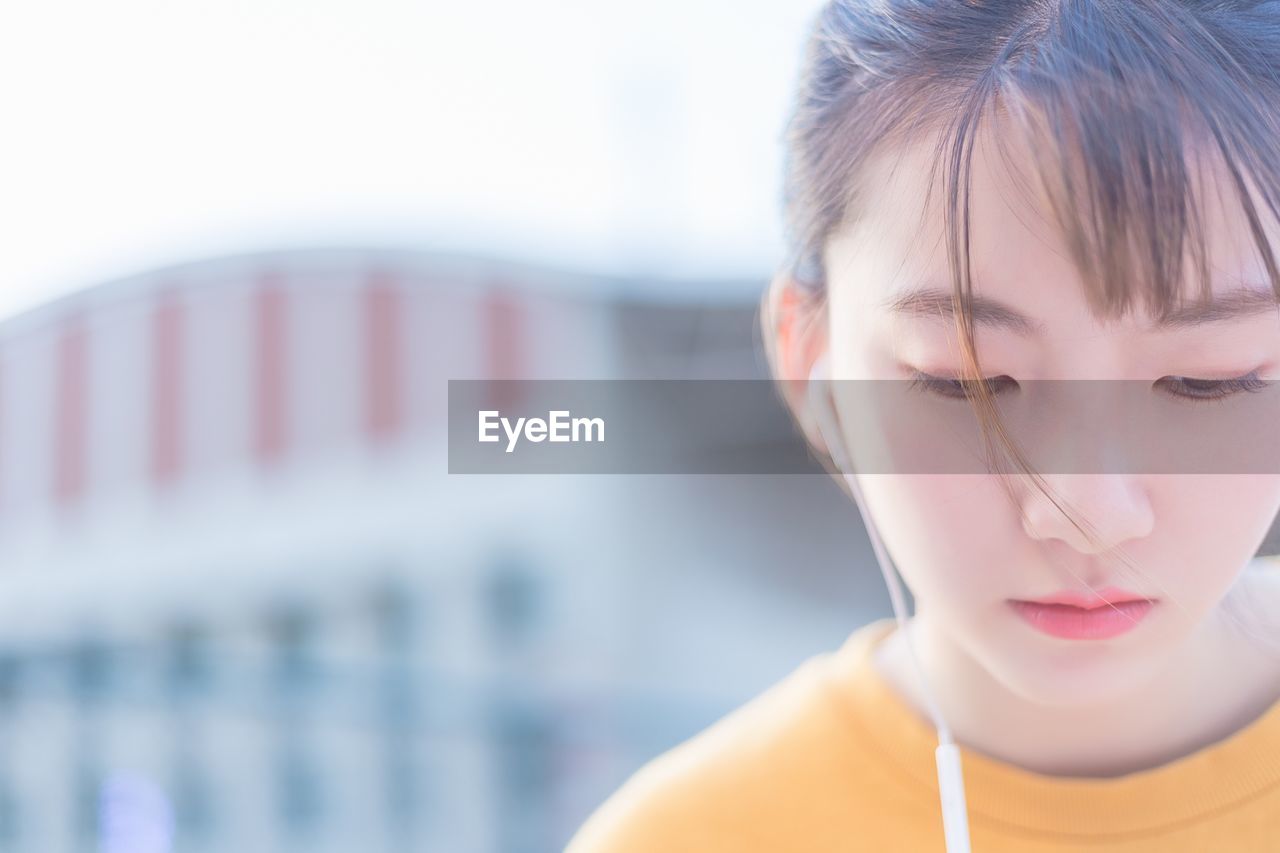 CLOSE-UP OF BEAUTIFUL WOMAN AGAINST CLEAR SKY