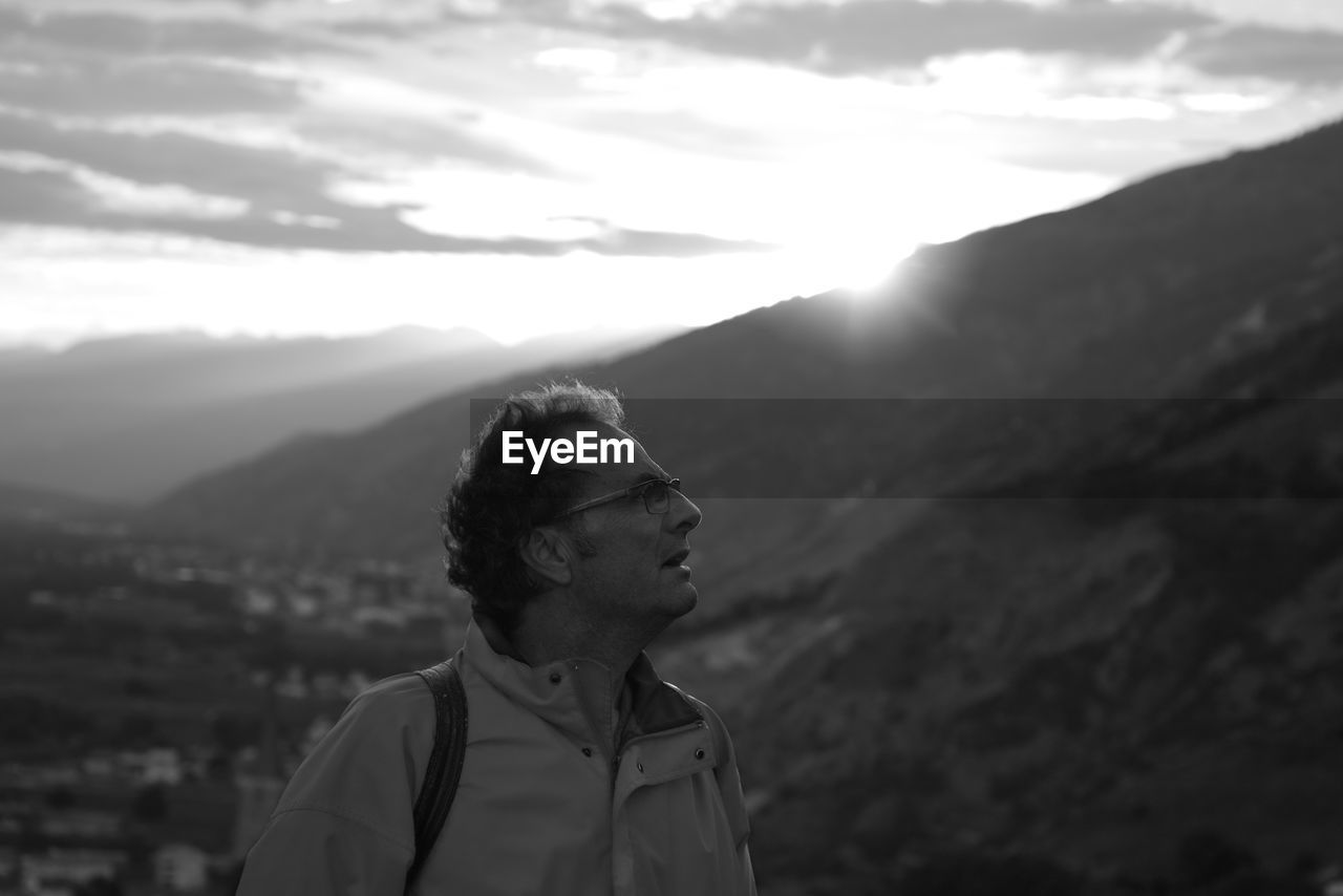 Man looking away while standing against mountain