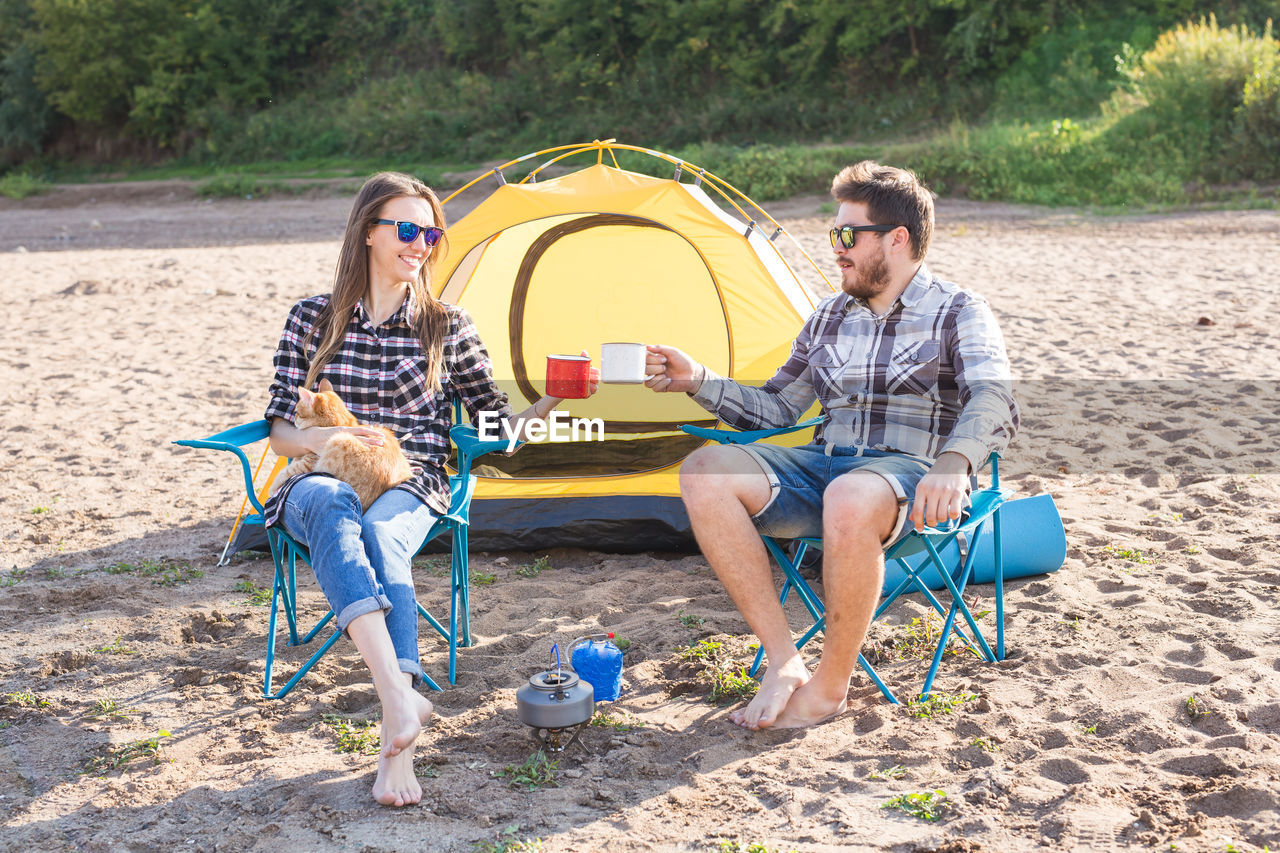 PEOPLE SITTING IN TENT ON LAND