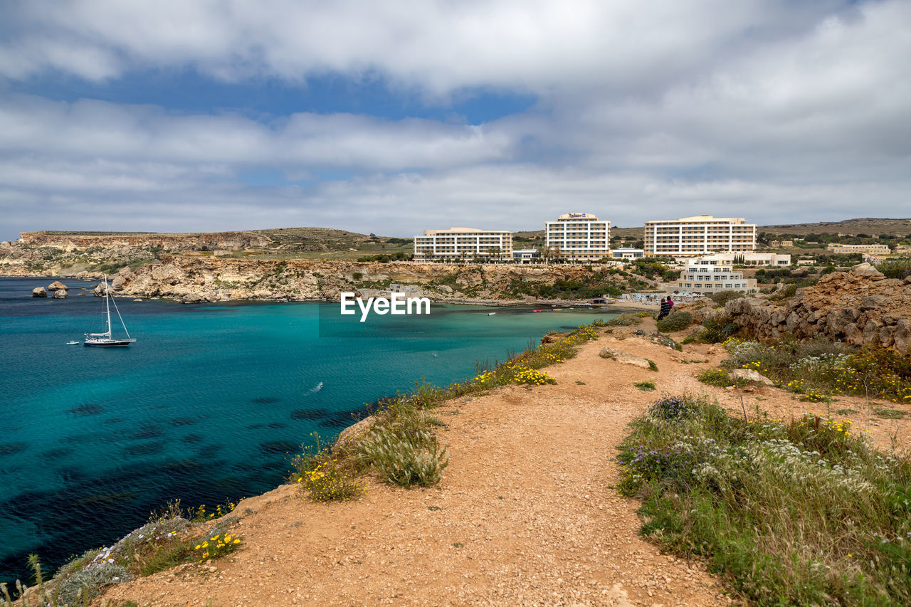 Scenic view of sea by buildings against sky