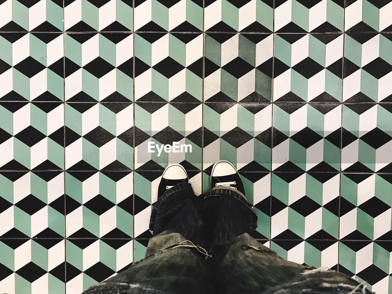 Low section of man standing on patterned tiled floor