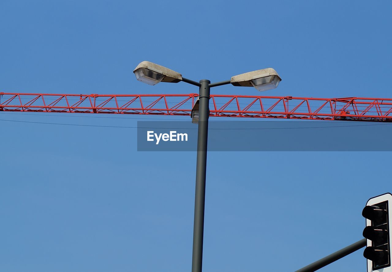 Low angle view of crane against clear blue sky