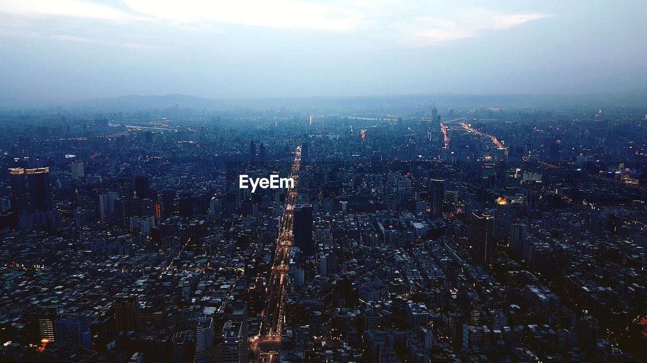 High angle view of illuminated buildings in city at dusk against sky