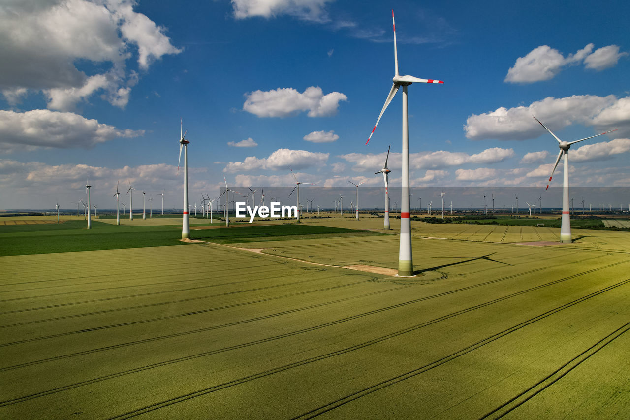 WIND TURBINES ON FIELD AGAINST SKY