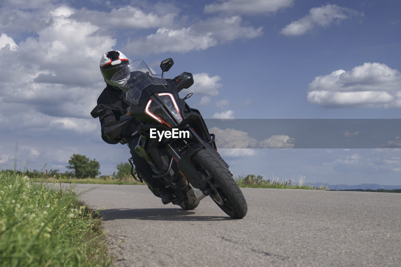 Man riding motorcycle on road against sky