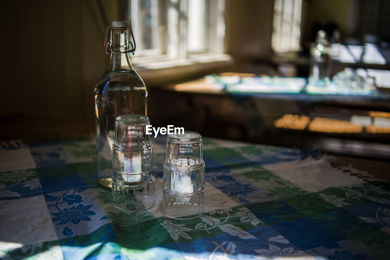 Close-up of glasses and bottle on table