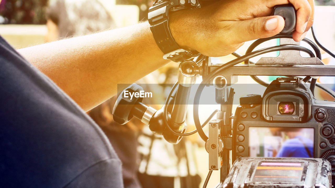 Cropped image of man touching video camera