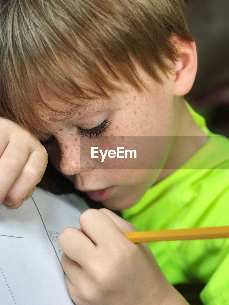 Close-up of boy writing in book with pencil