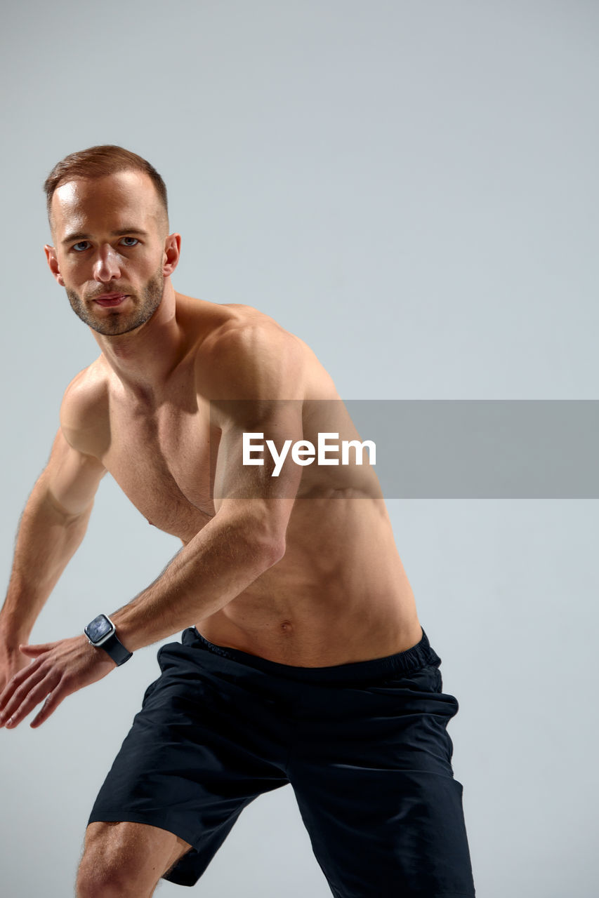 portrait of shirtless man standing against white background