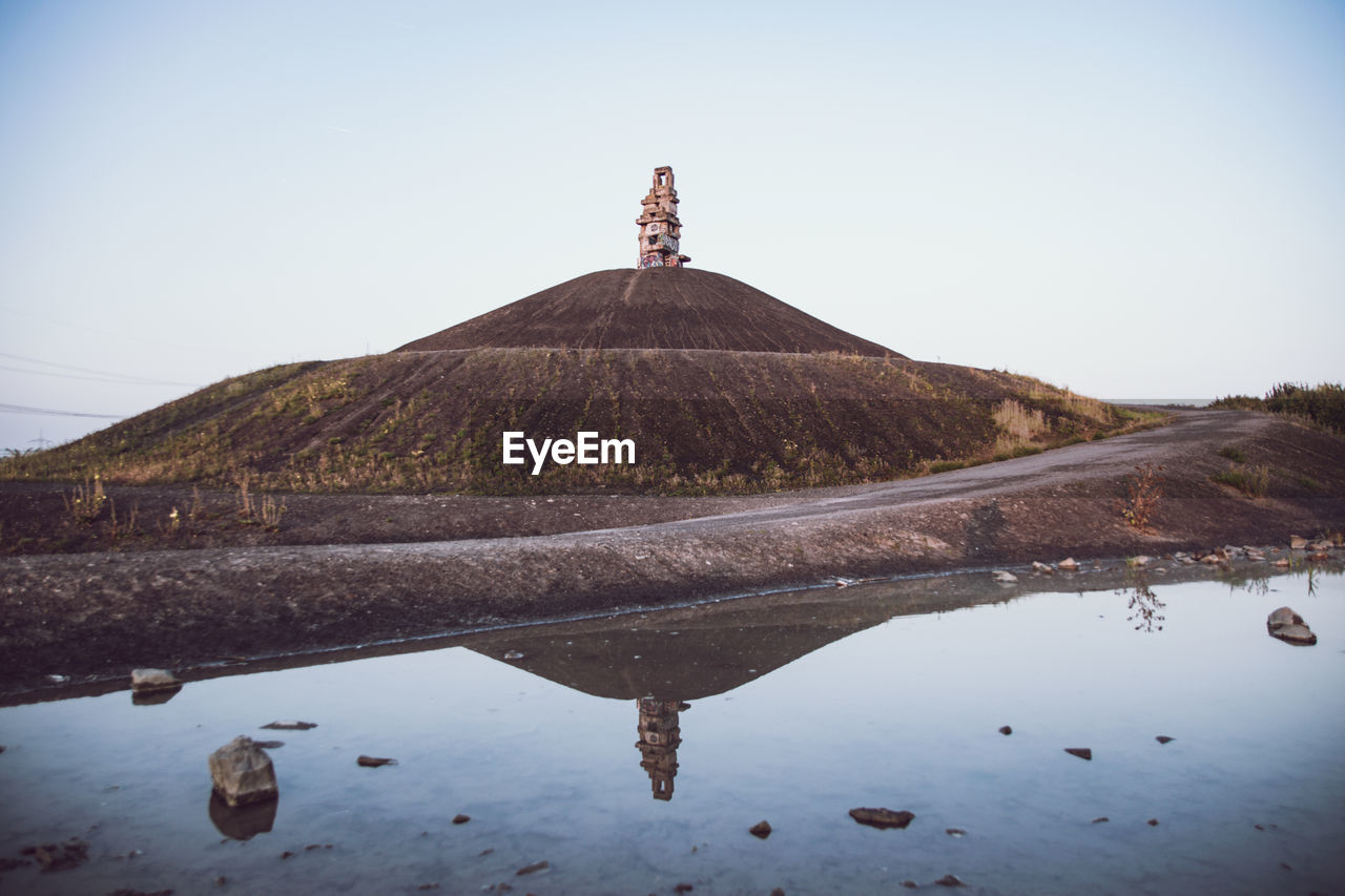 Built structure on land by mountain against clear sky