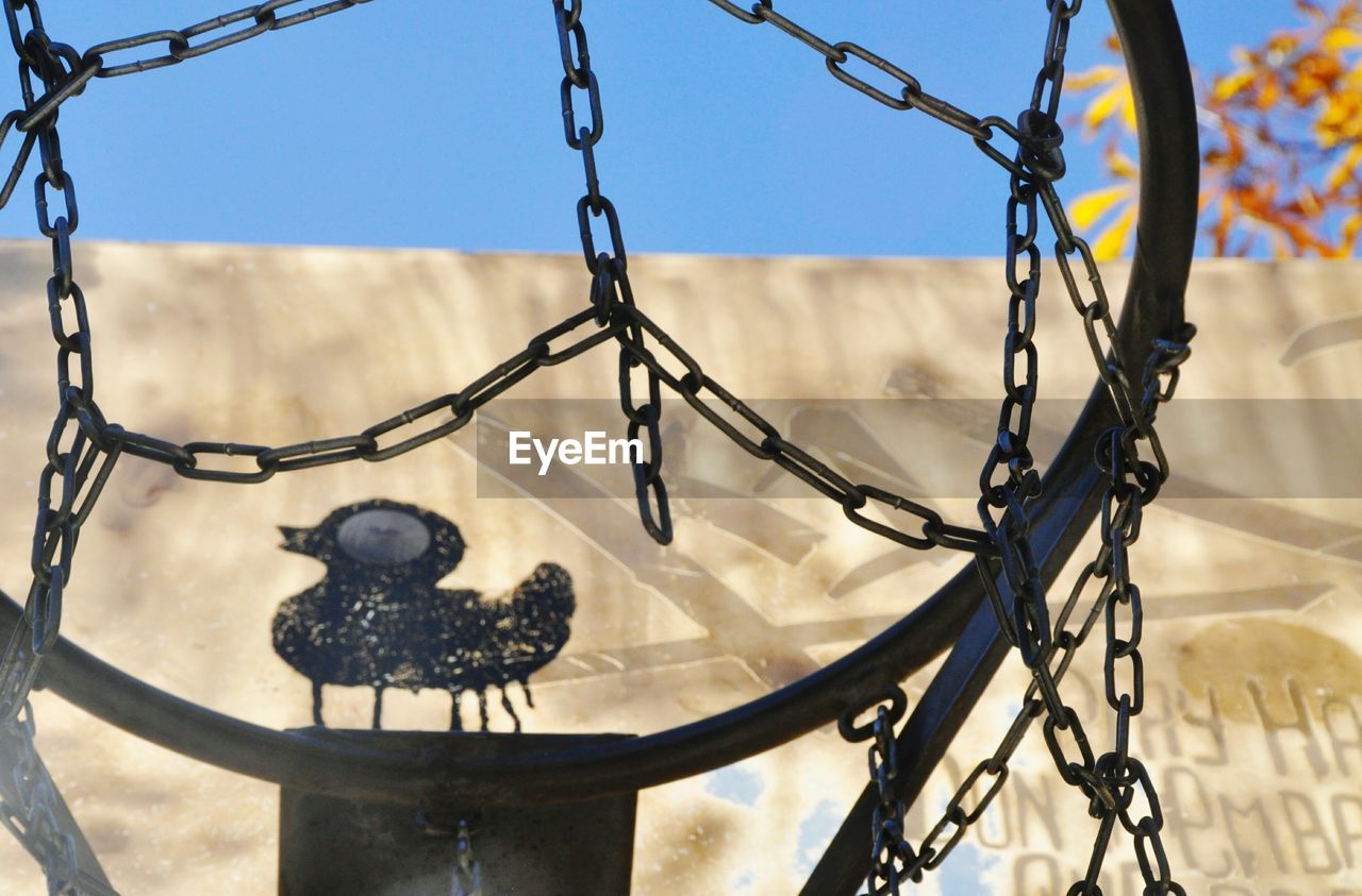 LOW ANGLE VIEW OF BIRDS ON METAL AGAINST SKY