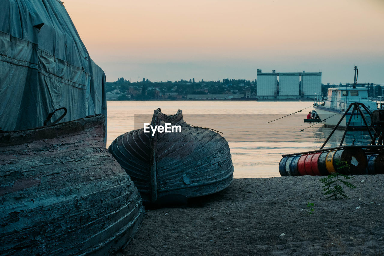 BOATS MOORED ON SEA AGAINST SKY DURING SUNSET