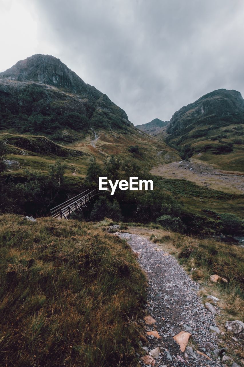 Scenic view of road by mountains against sky