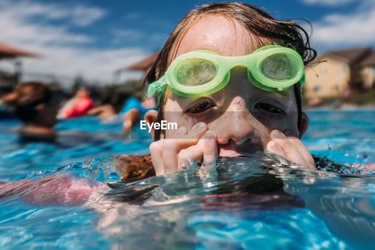 Young child wiping face in pool on summer day