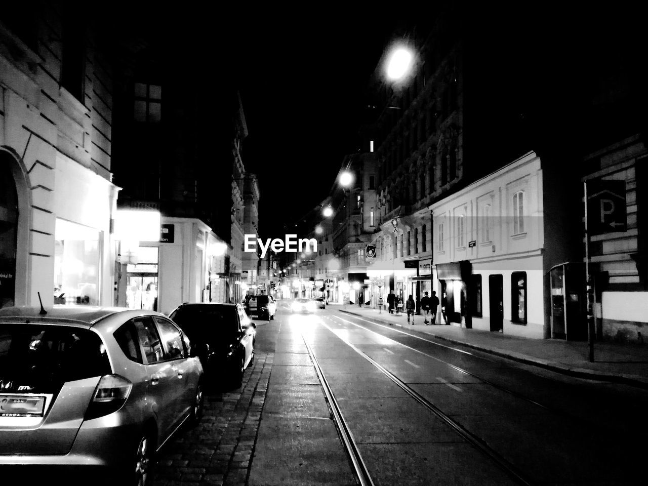 CARS ON CITY STREET BY BUILDINGS AT NIGHT