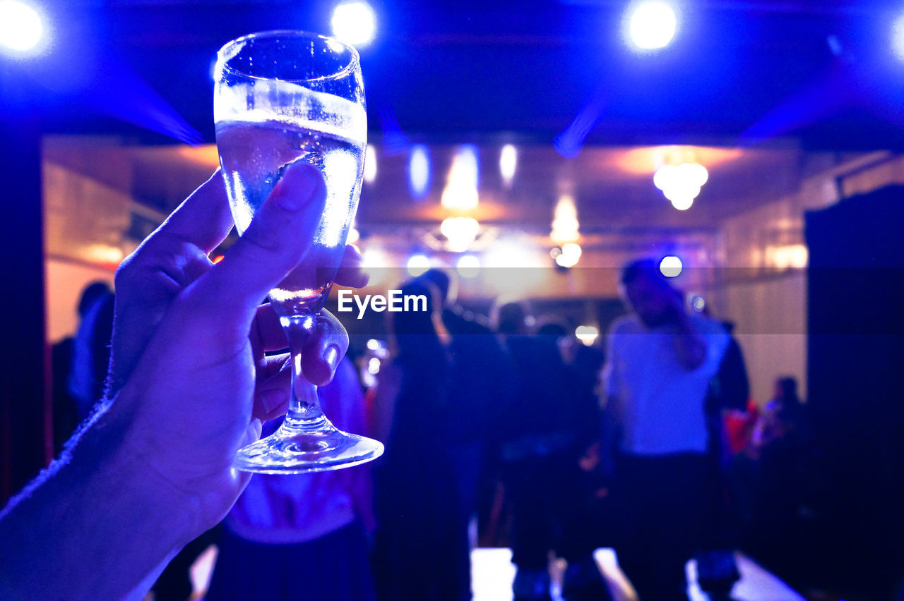 Close-up of hands holding drink during party at night