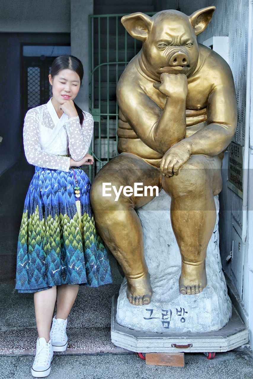 Full length of woman gesturing while standing by statue