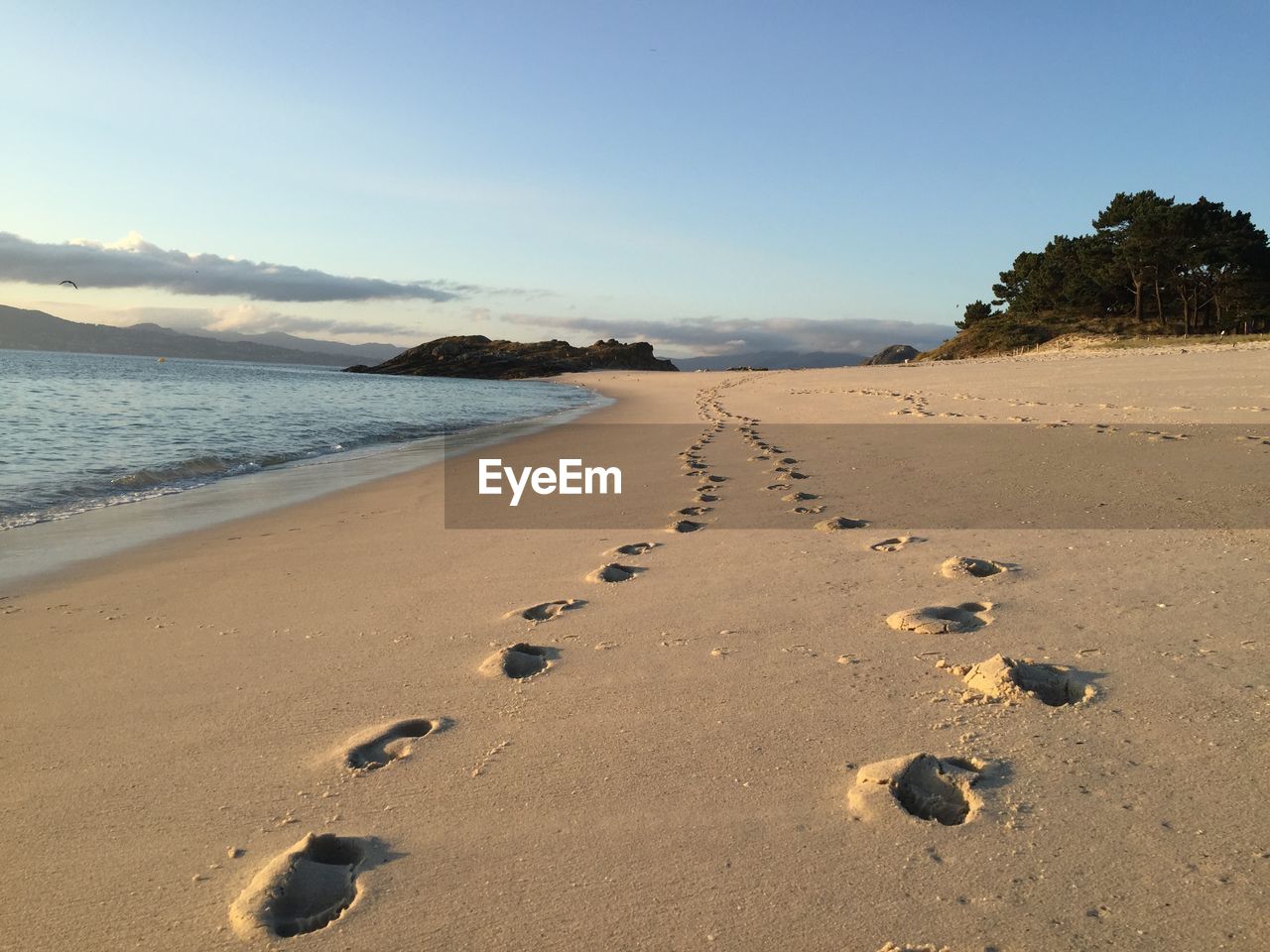 Footprints on sand at beach against sky