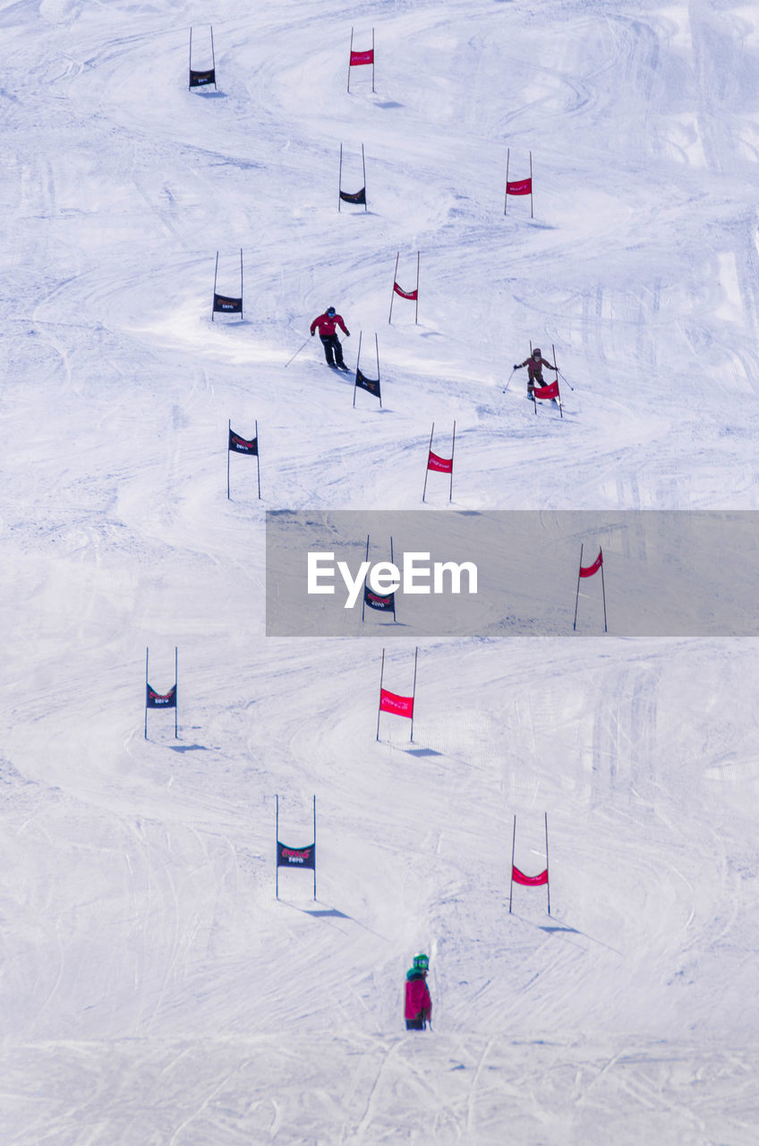 HIGH ANGLE VIEW OF PEOPLE SKIING ON FIELD