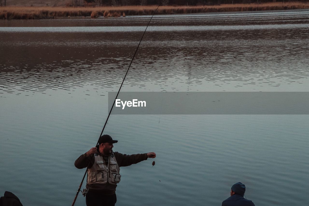 HIGH ANGLE VIEW OF MEN FISHING AT LAKE
