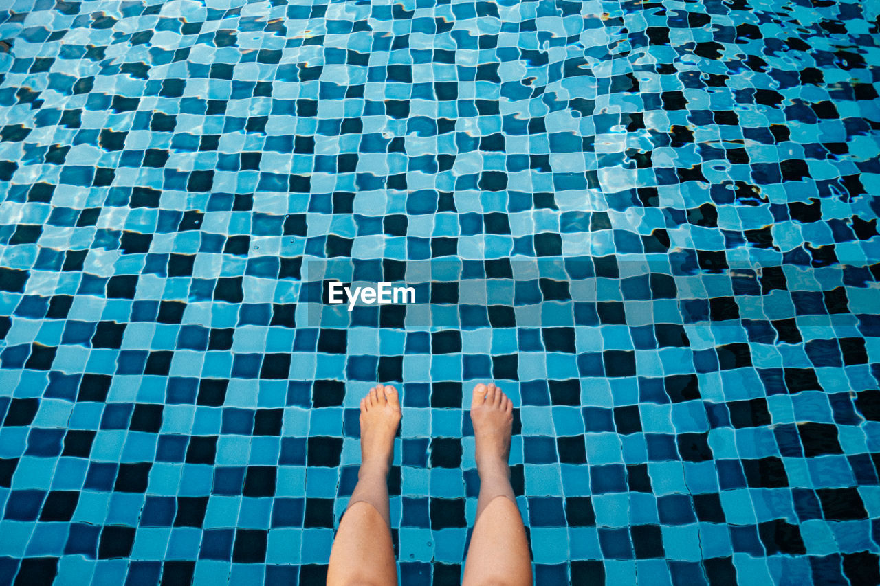 Low section of man relaxing in swimming pool