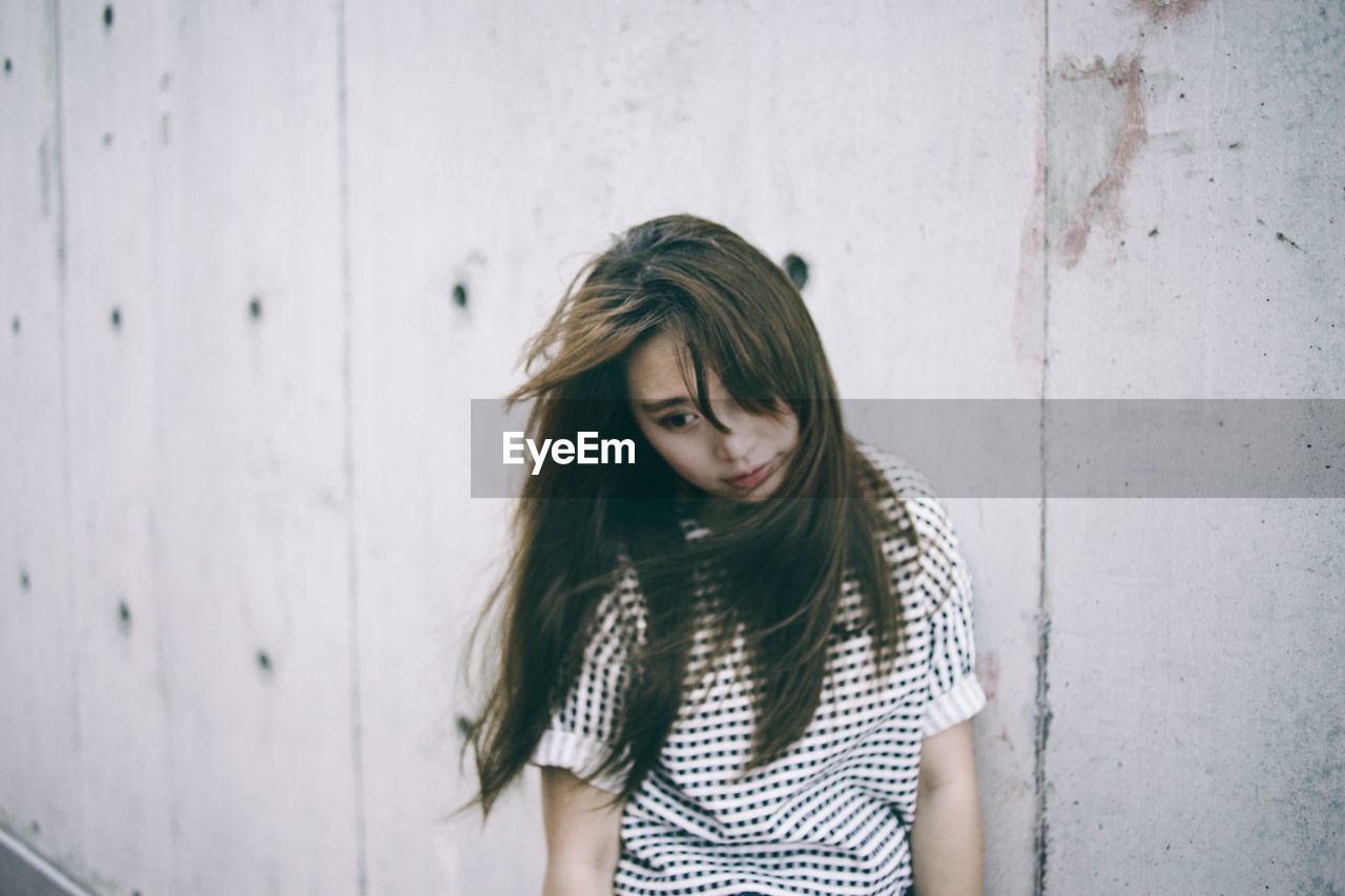 Thoughtful woman standing against wall