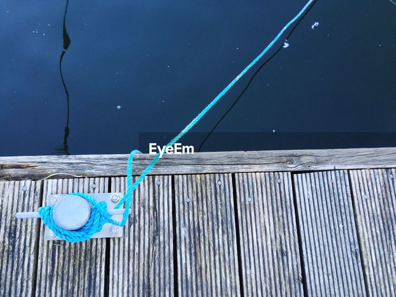 Directly above shot of rope tied to bollard on pier over lake