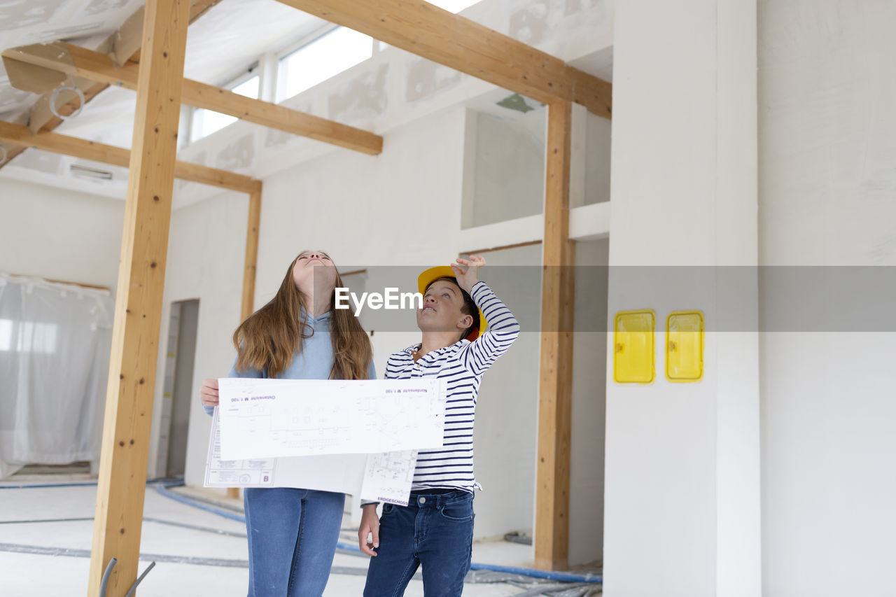 Girl holding plan standing at construction site