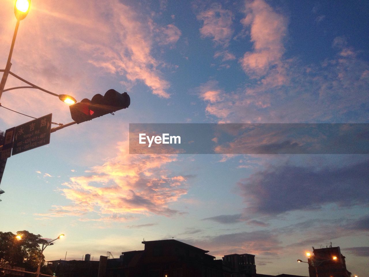 LOW ANGLE VIEW OF ILLUMINATED BUILDING AGAINST SKY AT DUSK