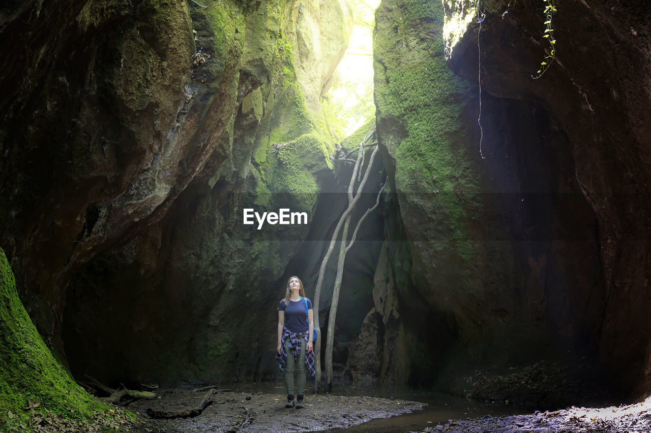 Female hiker standing amidst rock formations in forest