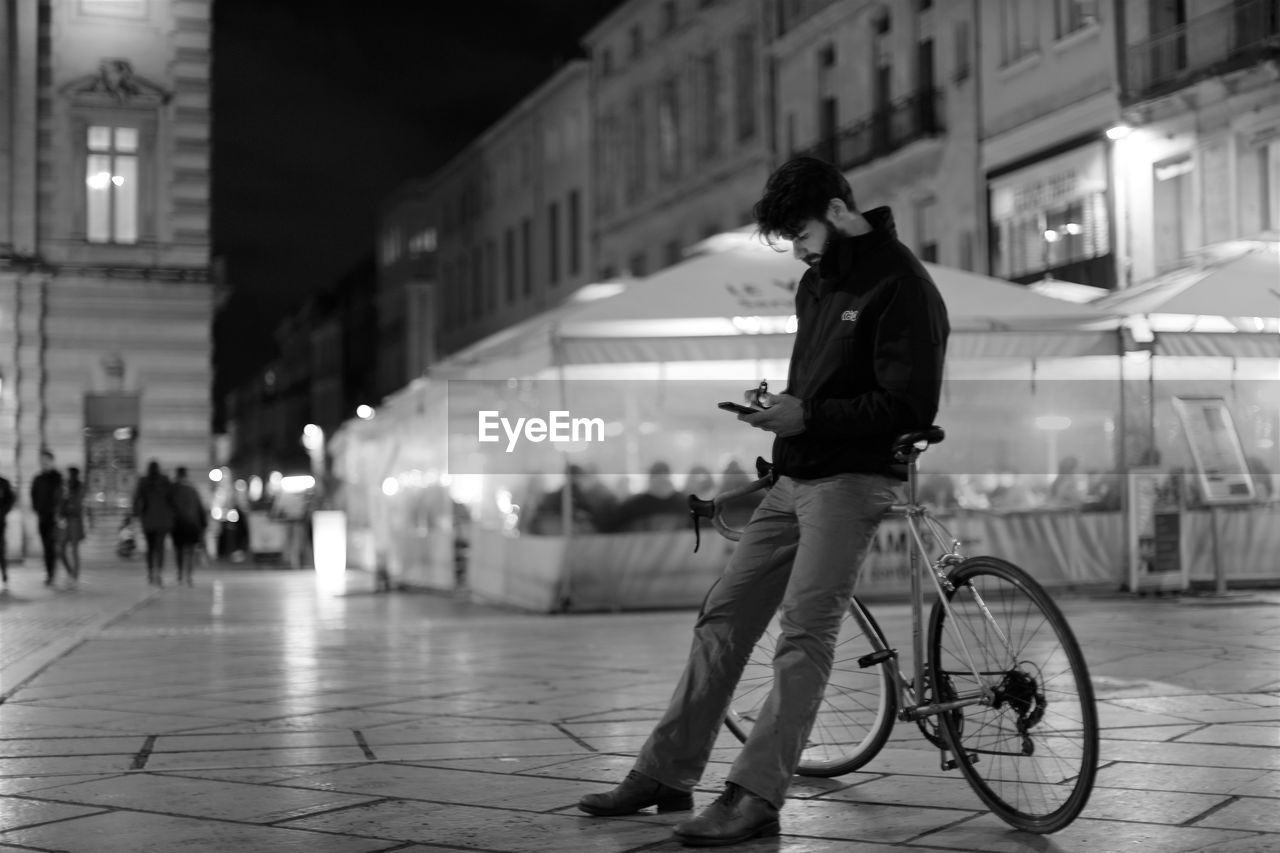 MAN RIDING BICYCLE ON STREET AT NIGHT