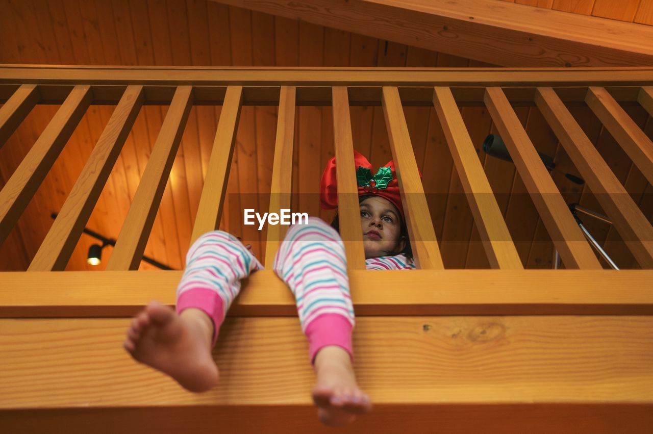 Low angle view of girl sitting at wooden railing during christmas