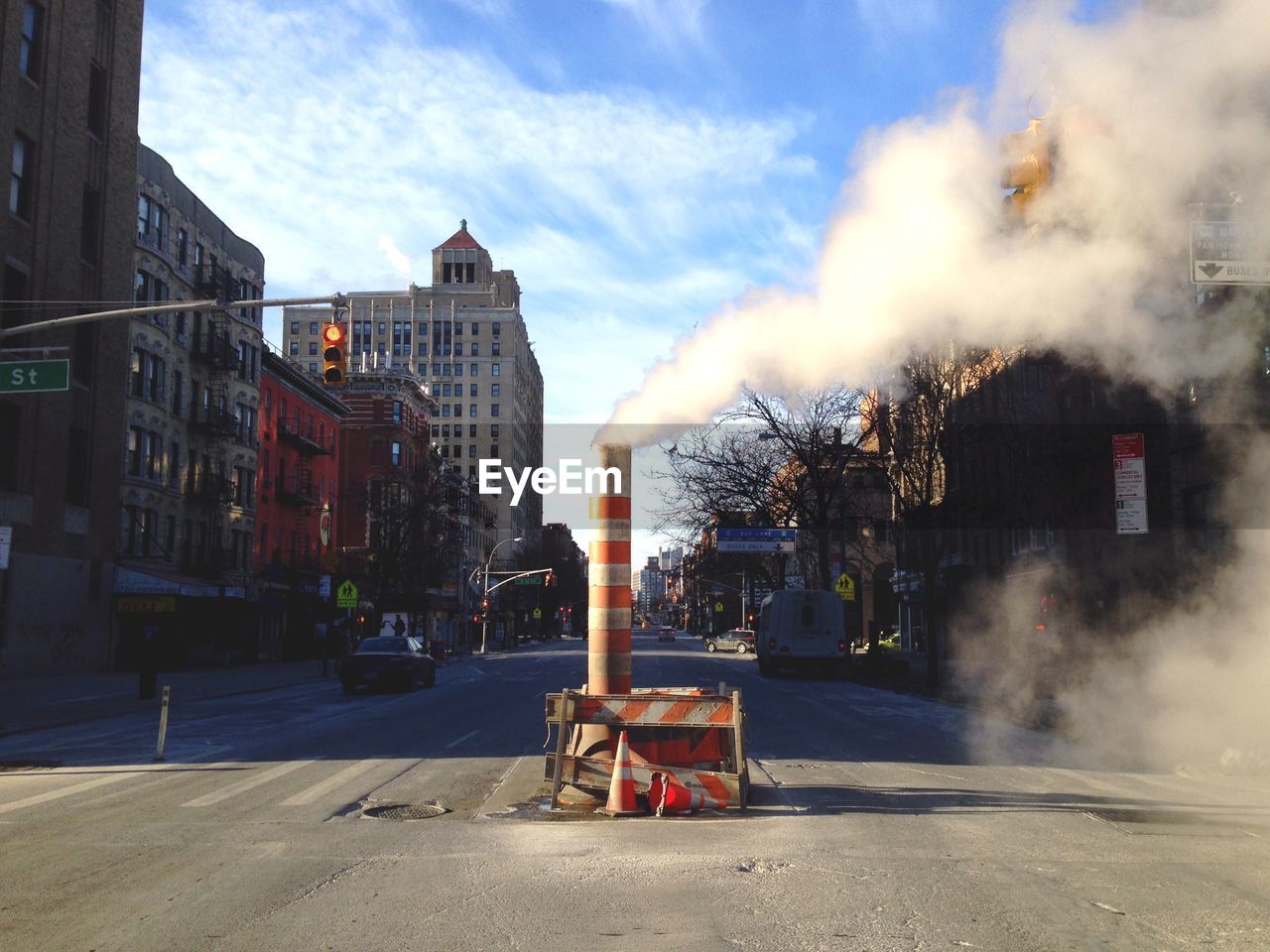 Smoke at construction site on street amidst buildings in city