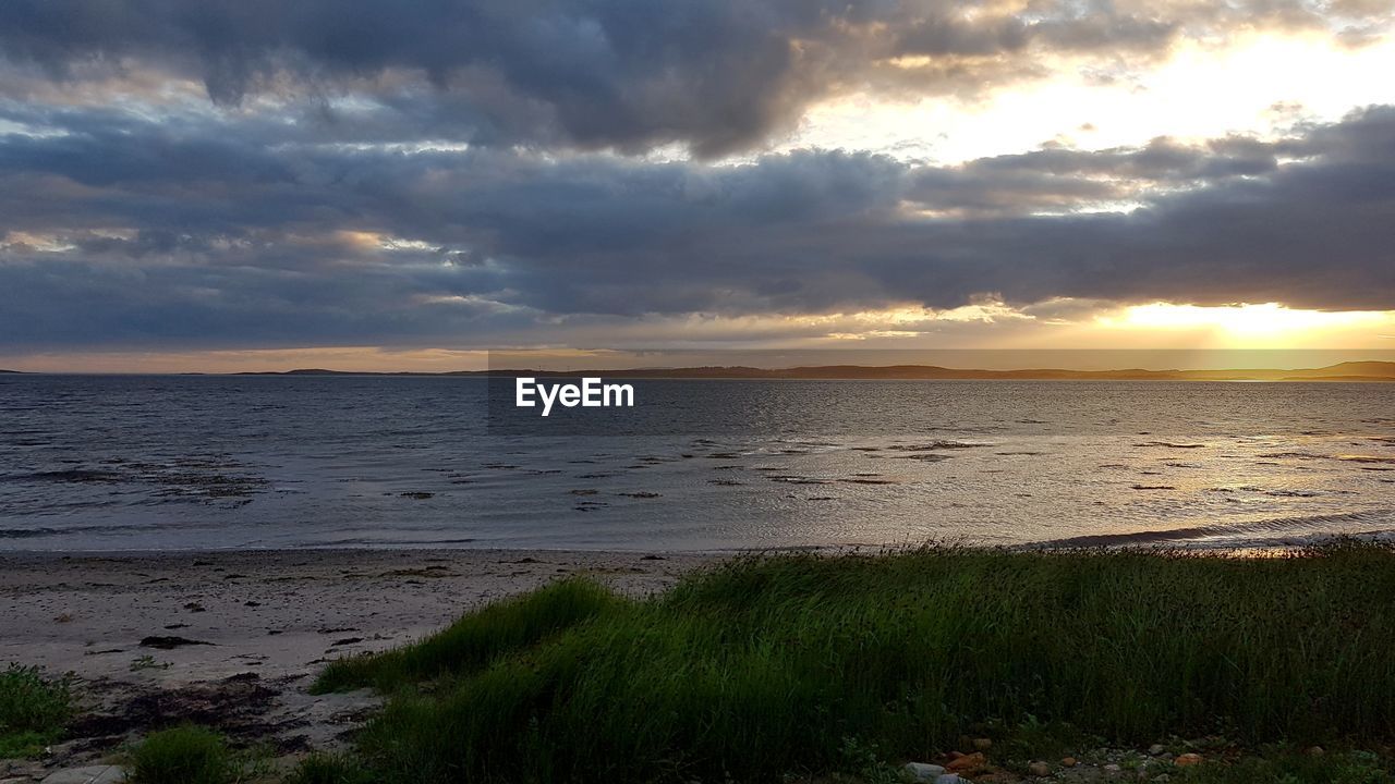 SCENIC VIEW OF BEACH AGAINST SKY DURING SUNSET