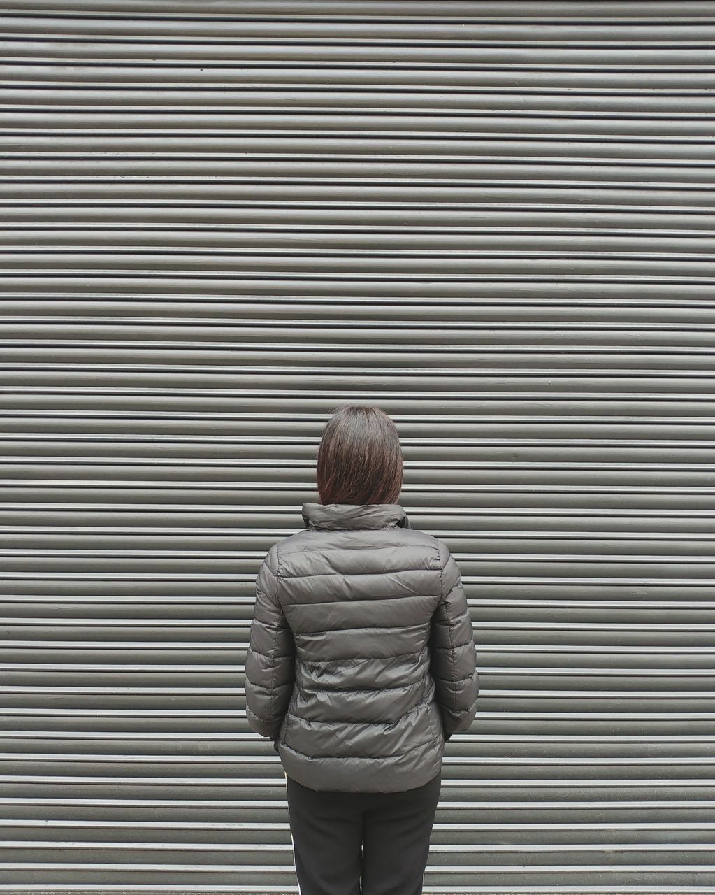 Rear view of woman standing against shutter