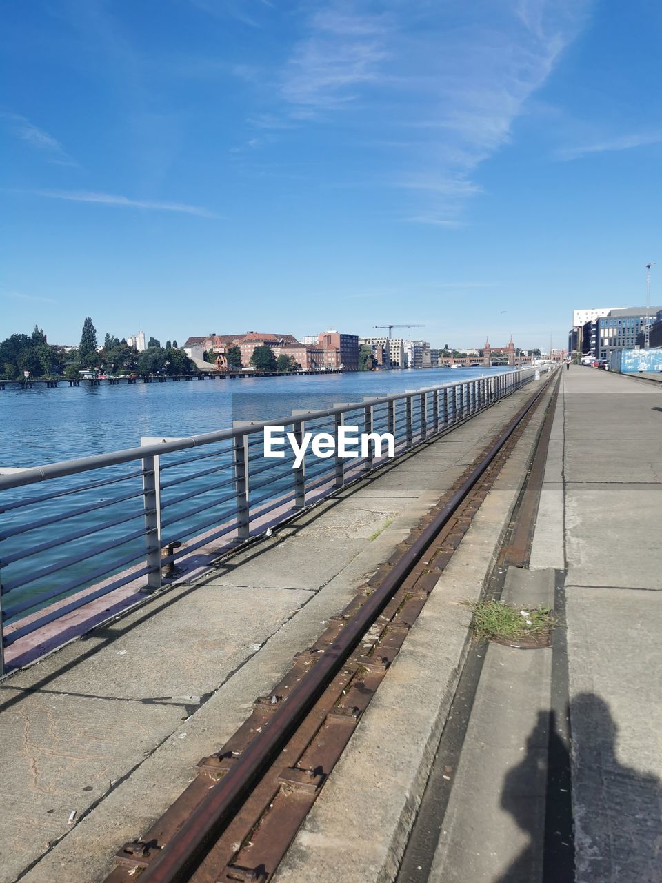 transportation, sky, water, architecture, walkway, nature, city, vehicle, mode of transportation, built structure, sea, travel, transport, coast, boardwalk, sunlight, travel destinations, day, blue, rail transportation, cloud, railroad track, track, building exterior, no people, outdoors, street, pier, road, horizon, sunny, beach, railing, tourism, footpath, bridge, land, shadow, clear sky, nautical vessel, vacation