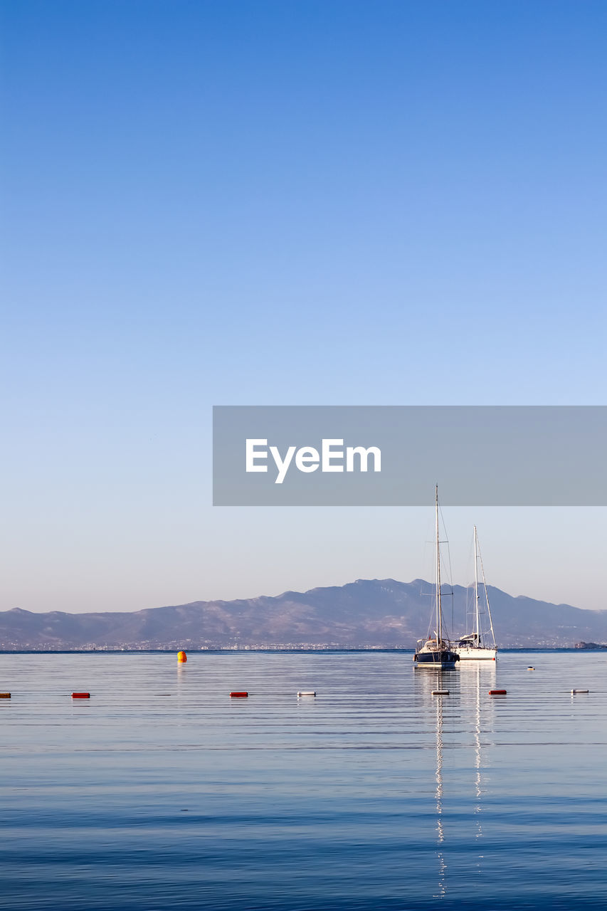 water, nautical vessel, transportation, sky, sea, blue, sailboat, mode of transportation, nature, clear sky, vehicle, ship, beauty in nature, copy space, boat, scenics - nature, travel, tranquility, horizon, sailing, tranquil scene, no people, day, travel destinations, bay, mountain, ocean, outdoors, pole, mast, sailing ship, sunny, idyllic, holiday, reflection, shore, watercraft, vacation, environment, trip, sunlight, land, yacht, landscape, beach, non-urban scene, summer