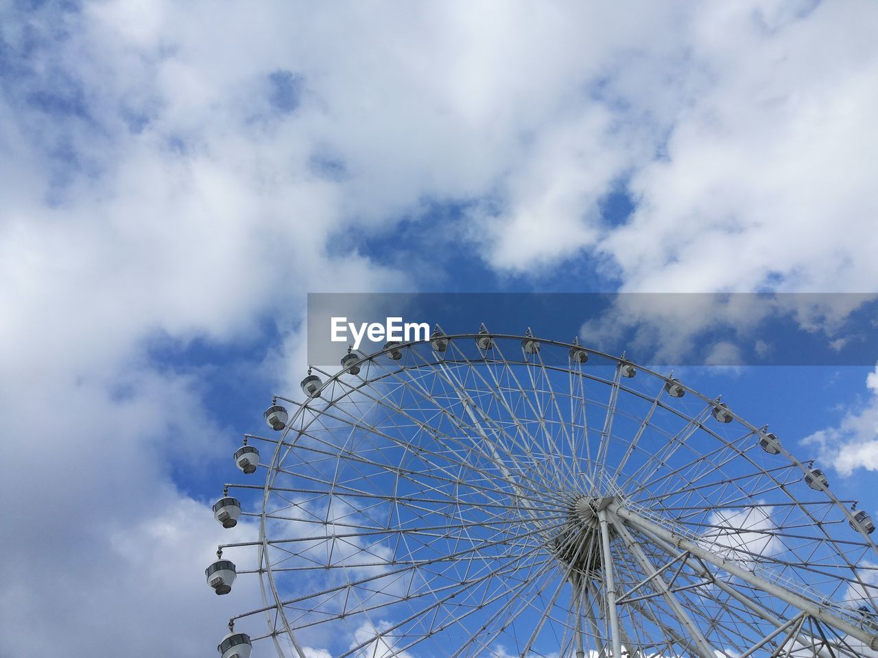 Low angle view of big wheel against blue sky
