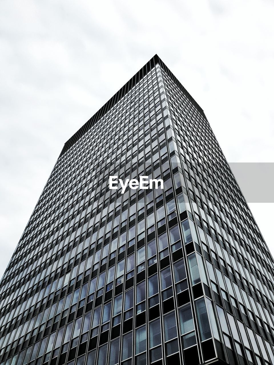 LOW ANGLE VIEW OF MODERN BUILDING AGAINST SKY IN CITY AGAINST CLOUDY DAY