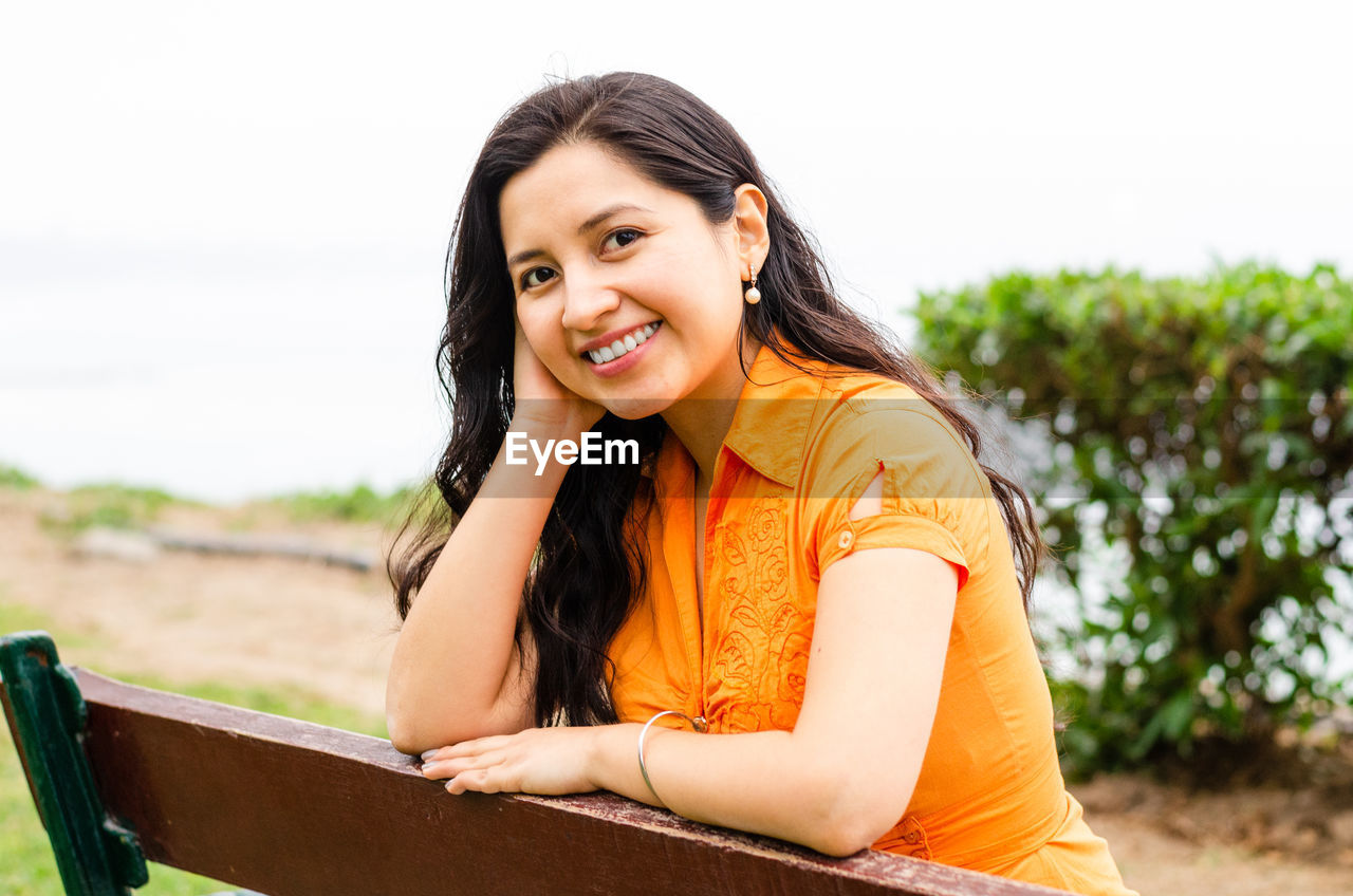 Portrait of smiling young woman against sky