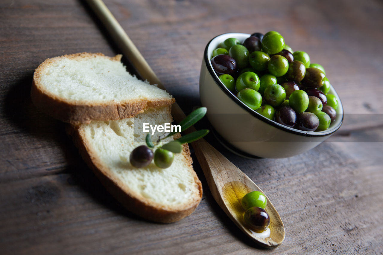 High angle view of green olives and bread on table