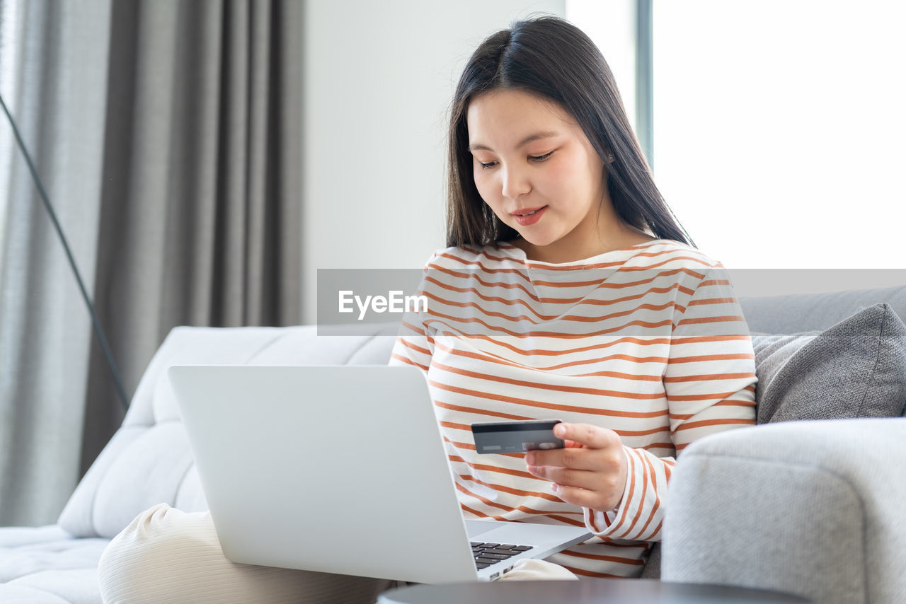 Happy woman making payment with credit card on laptop