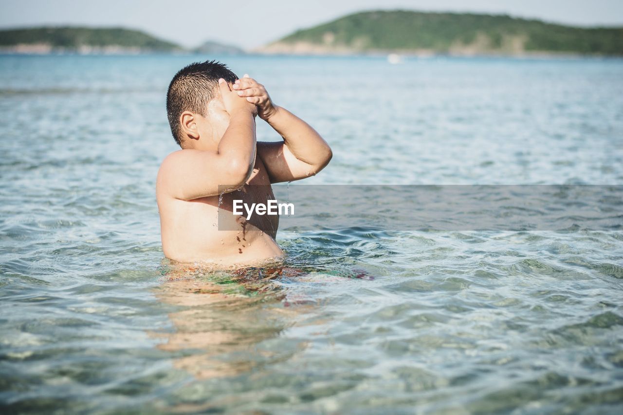 Shirtless boy swimming in lake