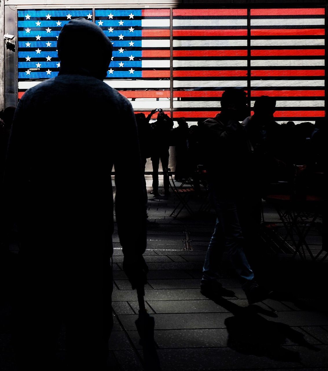 Silhouette of people standing in front of american flag