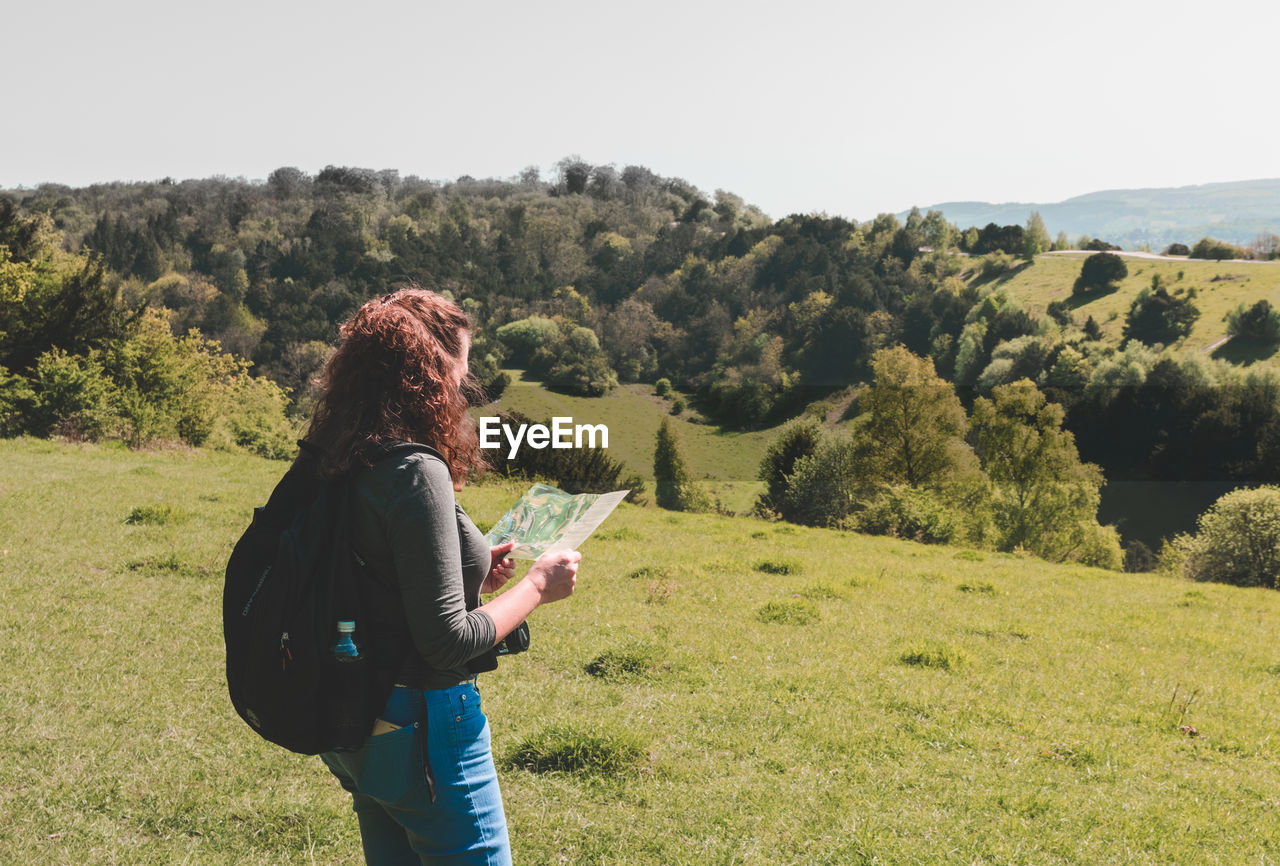 Woman looking at map while standing on field